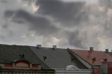 Dark sky with heavy grey clouds, over wet roofs