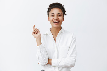 Successful attractive african-american businesswoman gazing with confidence and daring look at company who lost in competition, laughing out loud from joy, triumphing with coworkers