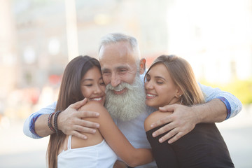 Happy Bearded senior man hugging his young friends.