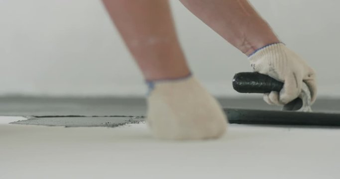 Slow motion closeup male worker applying micro concrete plaster coating on the floor with a trowel