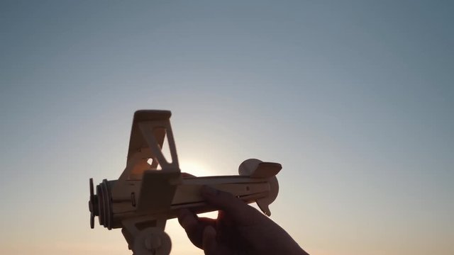 Child's hand with a wooden plane against the sunset