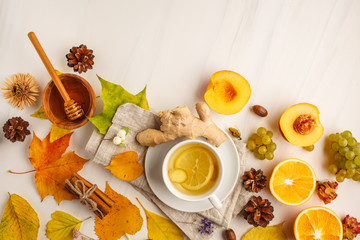 Autumn flat lay: tea, autumn fruits and decorations on a white background.