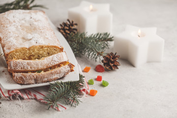 Fototapeta na wymiar Christmas bread with candied fruits and powdered sugar in Christmas decorations.