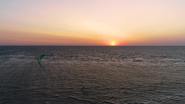 a pair of kitesurfers swim in the sea during sunset, aerial shooting