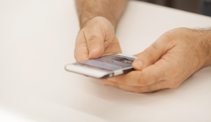 technology, business, retirement, people and leisure concept - close up of senior man hands with smartphone at table in office