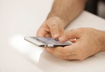 technology, business, retirement, people and leisure concept - close up of senior man hands with smartphone at table in office