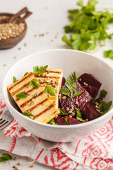 Baked beet salad with grilled tofu parsley and oil in a white bowl.