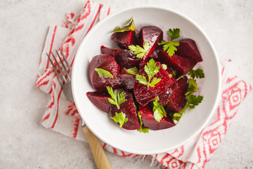 Baked beet salad with parsley and oil in a white bowl.