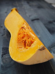 Quarter of bottle shaped pumpkin halved lying upon old wooden table. Selective focus on the center....