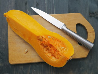 Top view of quarter of ripe pumpkin arranged upon cutting board. Cooking with butternut squash. Selective focus.