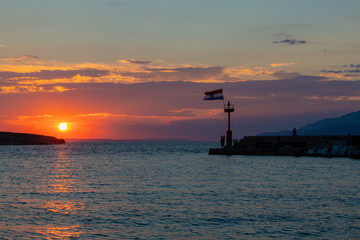 Obraz na płótnie Canvas Croatian flag flying in wind at sunset in harbor