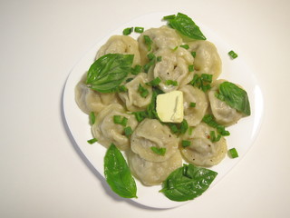 Boiled dumplings on a white background with Basil and a piece of butter.