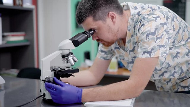Doctor in laboratory looking through microscope