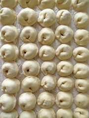 Lots of raw dumplings on a tray. Manty.