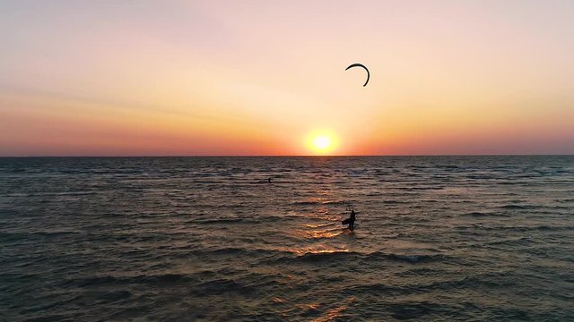 Kitesurfing in the sea at sunset, silhouette of a pair of kiters