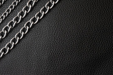 Metal silver chains on luxury black leather texture. - obrazy, fototapety, plakaty