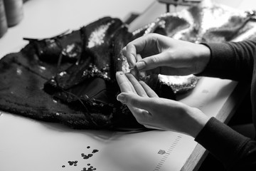 Seamstress sewing sequins on the dress