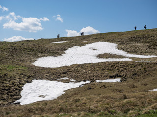 Wanderer über einem Schneefeld am Gipfelanstieg zum Zwisel, Tölzer Land, Bayern