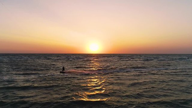 Beautiful sunset on the sea, a pair of kitesurfers glide along the waves