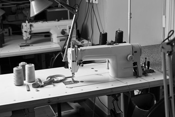 Professional seamstress working space with sewing machine, thread spools and measure tape on the...