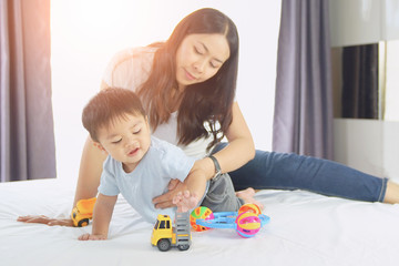 Happy loving family. Mother playing with her baby in the bedroom. Pretty woman holding a newborn baby in her arms, Mother with child playing educational toys 
