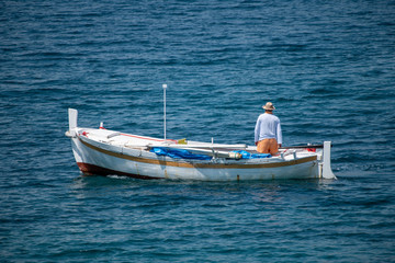 Fisherman in traditional wooden boat at sea