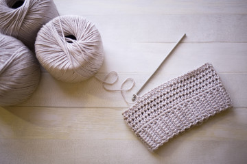 Handmade crochet tiny hat from grey cotton yarn, hobby crafts crocheting with steel hook, wooden background
