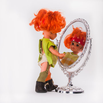 A Sloppy Girl-doll With Red Hair Looks At Herself In The Mirror. The Concept Of Appearance. Disorderly Herself.