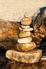 Pebble stack on the seashore. Pyramid of stones on the beach. Light at sunset. Symbol of patience. Concept of harmony and balance. Memory of the sea.