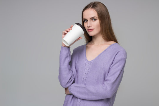 Girl in lilac jamper drinking coffee from paper plastic glass