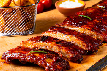 bbq spareribs on the plate with green salad and white sauce.