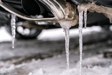 Fototapeta na wymiar Car exhaust pipe details with icicles, winter season