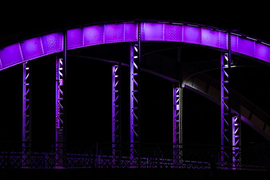 Fototapeta An old steel bridge in various colors, during the night