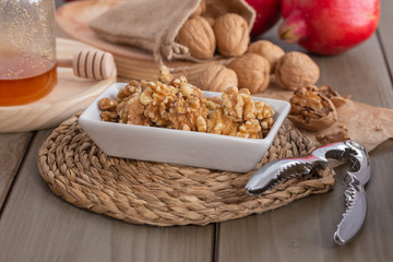 Walnuts, honey and pomegranates on a wooden kitchen table