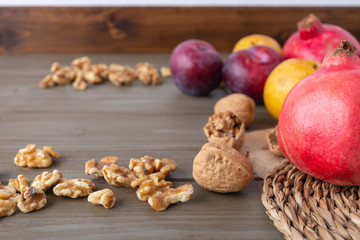 Plums, pomegranates and walnuts on a rustic wooden table