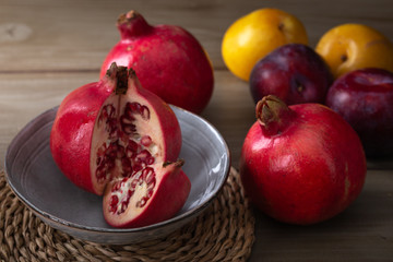 Pomegranates and plums on a wooden kitchen table