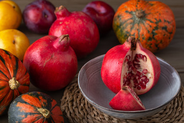 Pomegranates, gourds and plums on a kitchen table