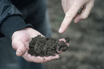 agronomist and farmer discuss the introduction of organic fertilizers and watering farming fields in early spring on a plowed field