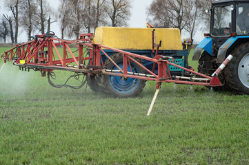 close-up view of the tractor spraying the chemicals on the large green field
