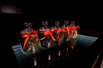 Five glass jars with red bows in which tea is filled