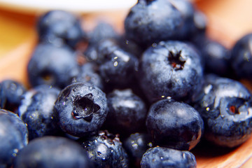 Fresh blueberry with drops of water in wooden bowl. Top view. Concept of healthy and dieting eating