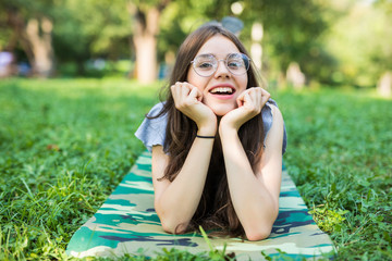 Cheerful woman lying down on a grass in park