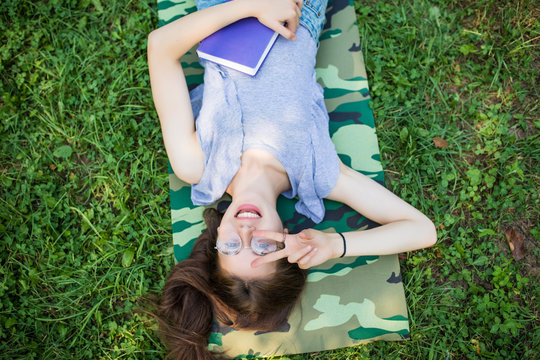 top view portrait of a pretty young woman relaxing on a grass in park