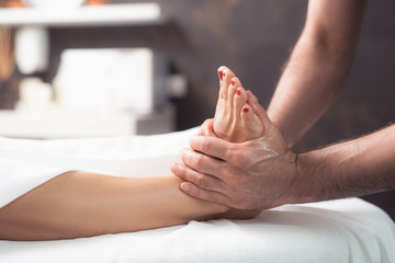 I love this procedure. Close up of male therapist hands massaging lady foot