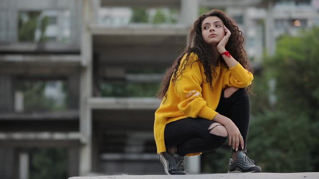 Teen girl in fashion yellow sweater sitting in urban city
