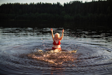 Elderly woman splashing in the summer river at village.