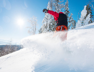 Horizontal low angle shot of a snowboarder riding the slope on a sunny winter day in the mountains....