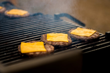 cook in gloves is cooking a cutlet with cheese for burgers on an open fire
