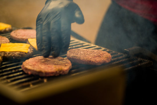  guy is cooking a cutlet with cheese for burgers on an open fire