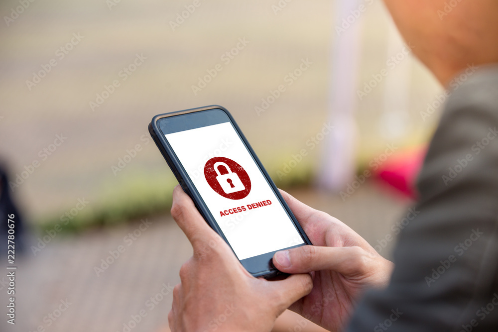 Aufkleber protection security system concept. man holding smartphone with access denied text on screen.